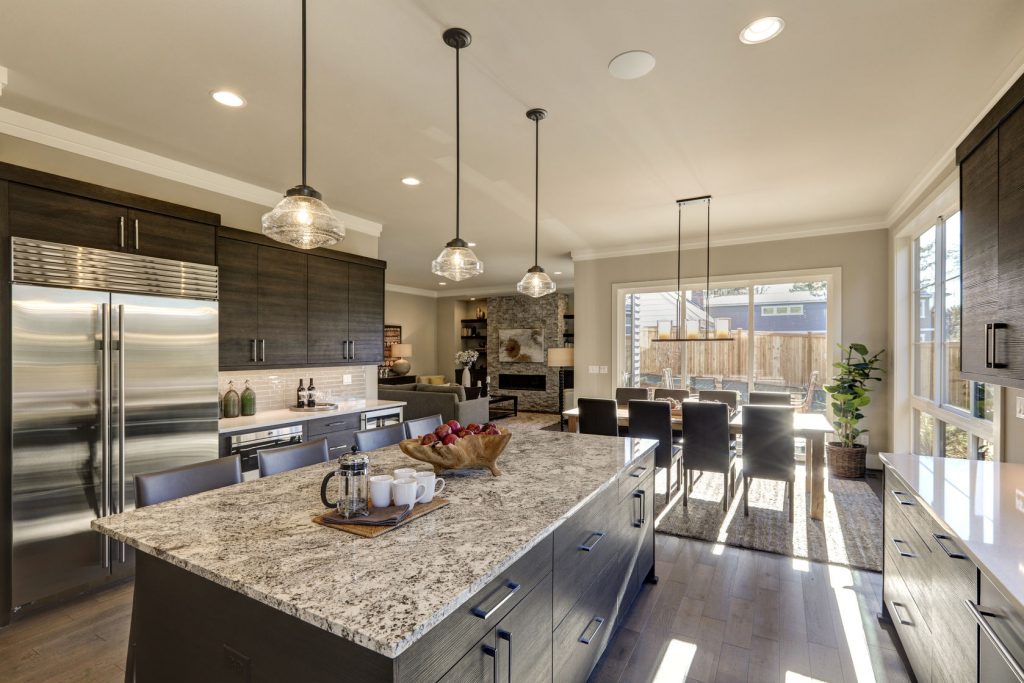 70156806 - modern gray kitchen features  dark gray cabinetry paired with white quartz countertops and a glossy gray linear tile backsplash. bar style kitchen island with granite counter. northwest, usa
