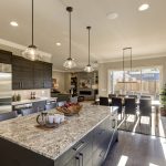 70156806 - modern gray kitchen features  dark gray cabinetry paired with white quartz countertops and a glossy gray linear tile backsplash. bar style kitchen island with granite counter. northwest, usa